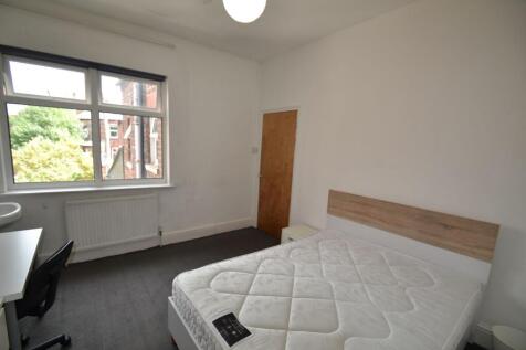 A well-lit bedroom featuring a large window wit...