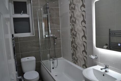 Modern bathroom featuring a bathtub with a glas...