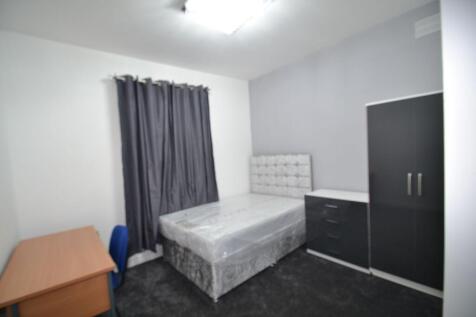 A modest single bedroom featuring a bed, a desk...