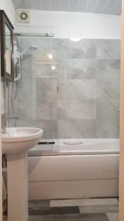 Bright, modern bathroom featuring a bath with i...