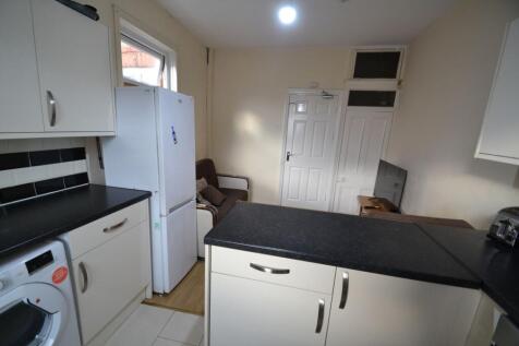 Compact kitchen with modern white cabinets, bla...