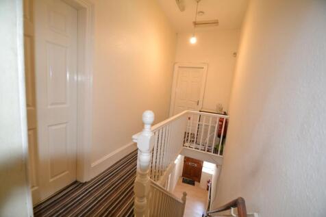 Bright upstairs hallway with striped runner, wh...