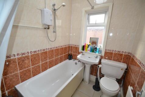 Tiled bathroom with a bathtub, overhead shower ...