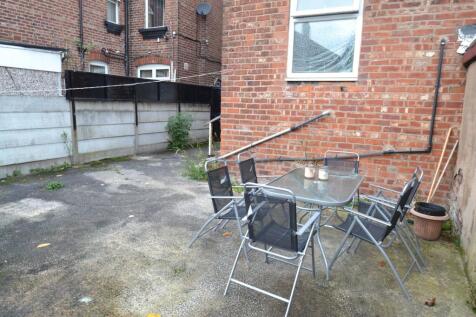 Paved private rear yard with brick boundary wal...