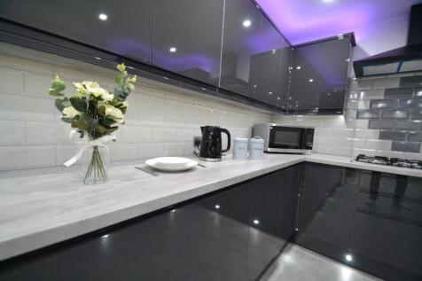 Modern and sleek kitchen featuring glossy black...