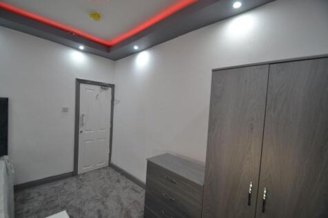 A clean, well-lit bedroom featuring neat wooden...