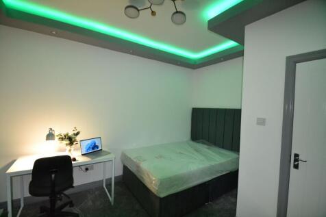 A well-lit single bedroom featuring a comfortab...