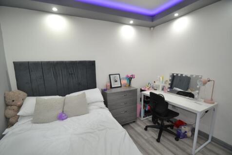 Bright, modern double bedroom with a padded gre...