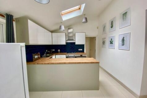 Bright modern kitchen with white cabinetry, a w...