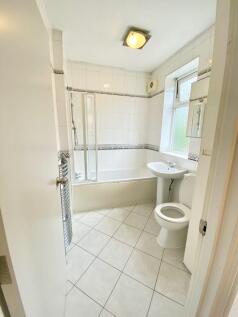 Bright, all-white bathroom with a bathtub and s...