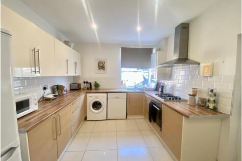 Bright, modern galley kitchen with light wood a...