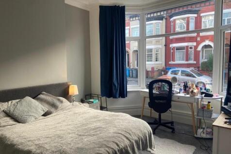 A well-lit bedroom featuring a comfortable doub...