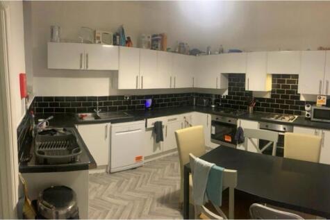 Modern kitchen area featuring white cabinets, a...