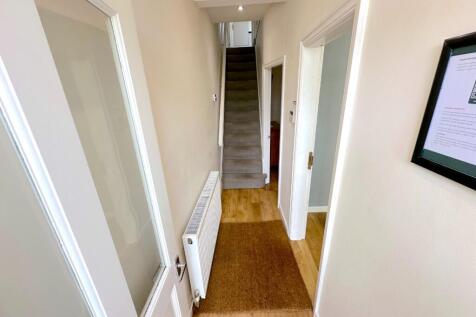 Bright, neutral hallway with light wood floorin...