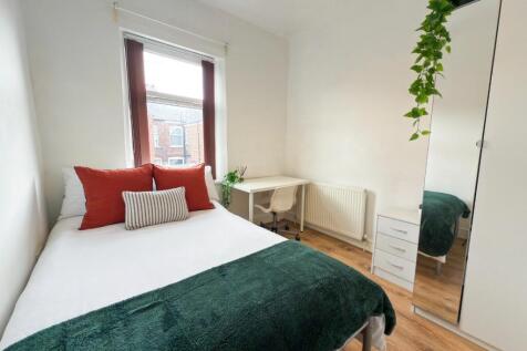 A bright and welcoming bedroom featuring a comf...