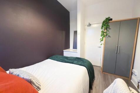 A cozy single bedroom featuring a neatly made b...