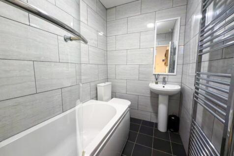 A clean, modern bathroom featuring a bathtub, a...