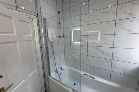 Bright, modern bathroom with a white bathtub, g...