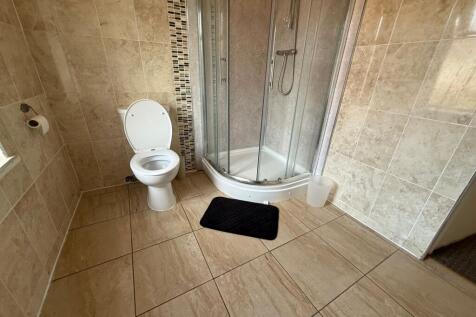 Bright, tiled bathroom with a corner glass show...