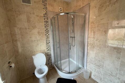 Bright, tiled bathroom with a modern corner sho...