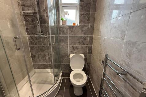 Modern tiled bathroom with a curved glass showe...