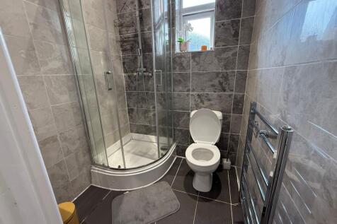 Modern tiled bathroom with a curved glass showe...