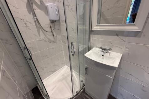 Bright, modern bathroom with a corner glass sho...