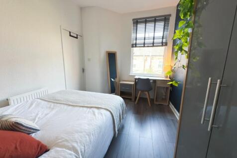 Bright double bedroom with a neatly made bed, s...
