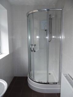 Bright tiled bathroom with a curved glass showe...