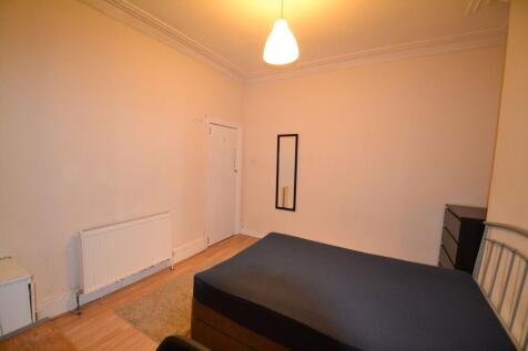 A modest bedroom with a single bed, illuminated...