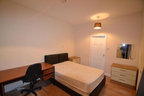 A well-lit bedroom featuring a double bed with ...