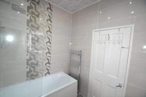 Modern bathroom featuring a bathtub, tiled wall...