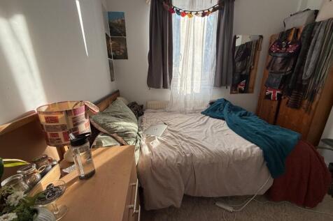 Cozy double bedroom with a large window dressed...