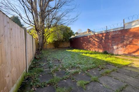 Sunlit private rear garden with a paved patio a...