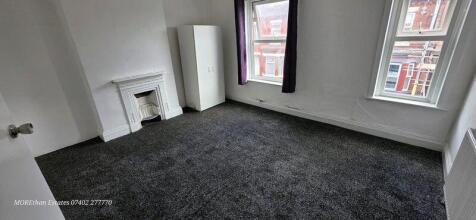 Bright master bedroom featuring two large windo...