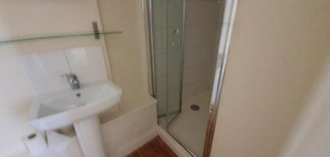 Clean compact bathroom with a pedestal sink, gl...