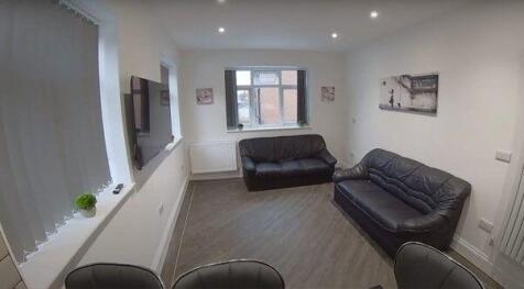 Bright, tidy living room with two leather sofas...