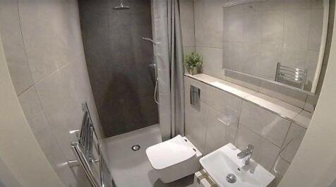 Modern, tiled bathroom with a wall-hung toilet,...