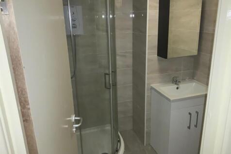 Modern tiled bathroom with a curved glass showe...