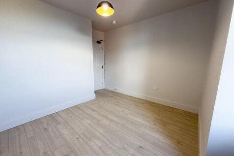 Clean, neutral single bedroom with light wood f...