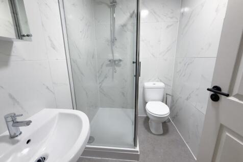 Bright, modern bathroom featuring a walk-in gla...