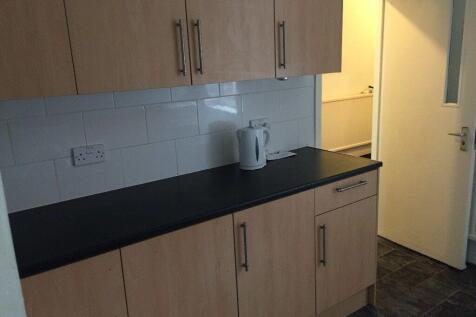 Compact kitchen with light wood cabinets, black...