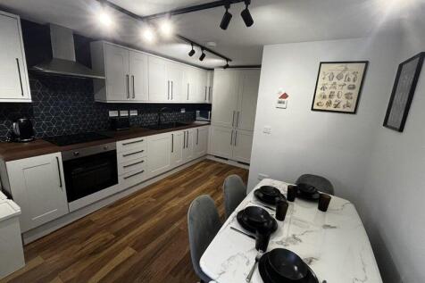 Modern fitted kitchen with long run of white ca...