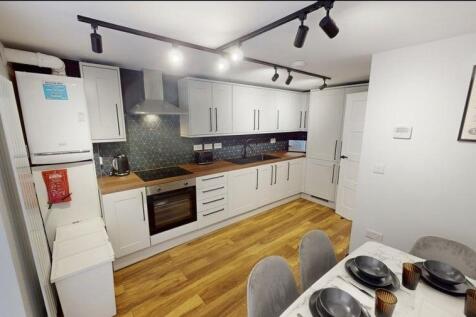 Modern fitted kitchen with white cabinetry, woo...