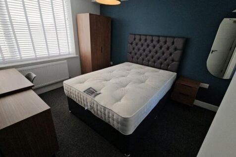 Bright, neatly furnished bedroom with a comfort...