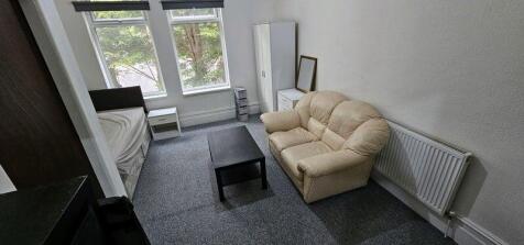 Well-lit furnished bedroom with large front win...