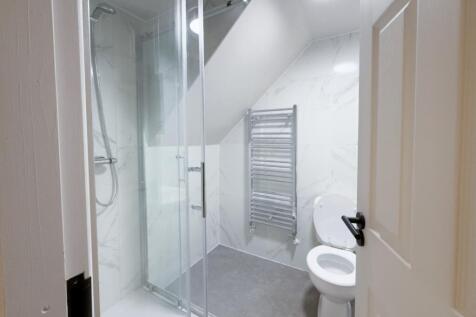 Modern white bathroom with a glass-enclosed wal...