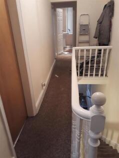 Bright upstairs hallway with neutral decor, car...