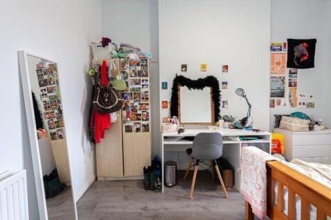 A bright and tidy room featuring a desk with a ...