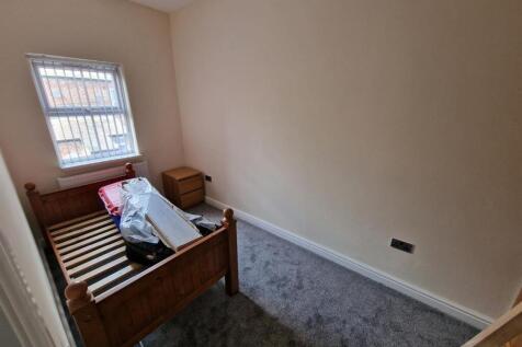 Cozy single bedroom featuring a wooden bed fram...